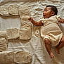 baby, infant, child, knitwear, blanket, number_five, cushion, soft_texture, lying_down, celebration, cute, skin, expression, hand, foot, indoors, fabric, pattern, comfort, milestone