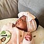 baby, sleeping, headband, bow, pink, knitted_sweater, cushion, milestone_card, lion, stars, infant, peaceful, closeup, portrait, cute, one_month, child, soft_lighting, indoors, cozy