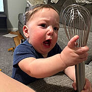 Jackson joined the competition — help win amazing prizes! baby, child, whisk, kitchen_tool, expression, face, chubby_cheeks, indoor, couch, carpet, clothing, short_sleeve, person, hand, grip, living_room, curtains, furniture, hair, tongue_out