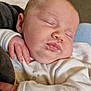 baby, sleeping, infant, white_clothing, hand, face, peaceful, cozy, soft_fabric, newborn, child, portrait, indoor, closeup, skin, head, cheeks, person, rest, comfort