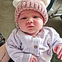 baby, child, infant, hat, knit_hat, pom_poms, cardigan, clothing, person, indoor, carpet, sofa, hand, face, cute, pink, white, floral_pants, cozy, home