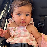 Zanara is registered to the contest to win money with this photo: baby, child, car_seat, pink, hair_clip, flower, curious, infant, seatbelt, clothing, blanket, face, portrait, young_child, cute, sitting, indoors, closeup, person, button