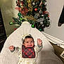 Zanara joined the competition — help win amazing prizes! baby, infant, smiling, happy, headband, plaid_bib, blanket, christmas_tree, ornaments, holiday, decorations, indoor, cozy, celebration, festive, child, person, cute, joyful, portrait
