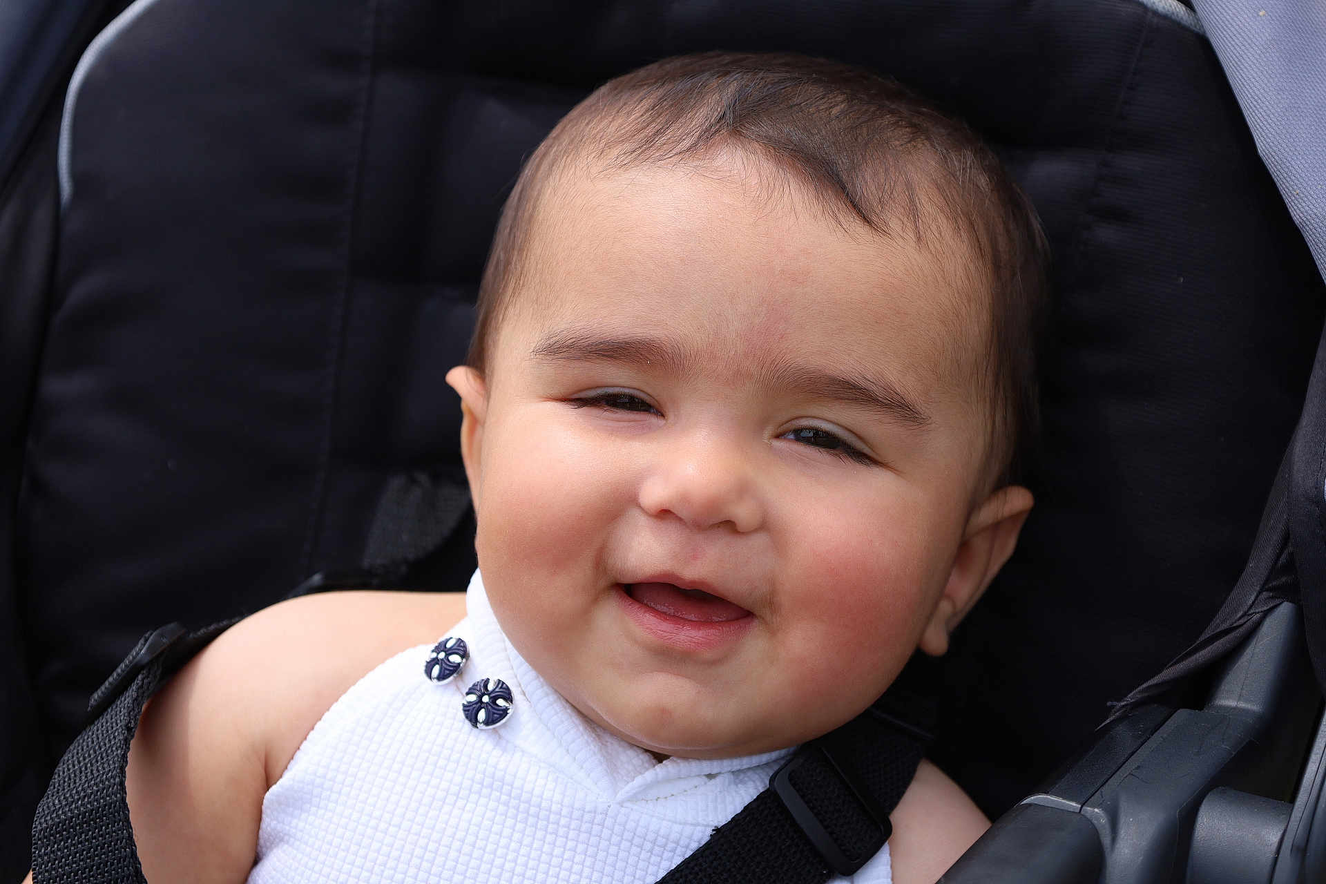 Vedika is registered to the contest to win money with this photo: baby, child, face, smile, stroller, seatbelt, clothing, button, head, skin, cheek, person, infant, cute, portrait, closeup, seat, babywearing, happy, outdoor