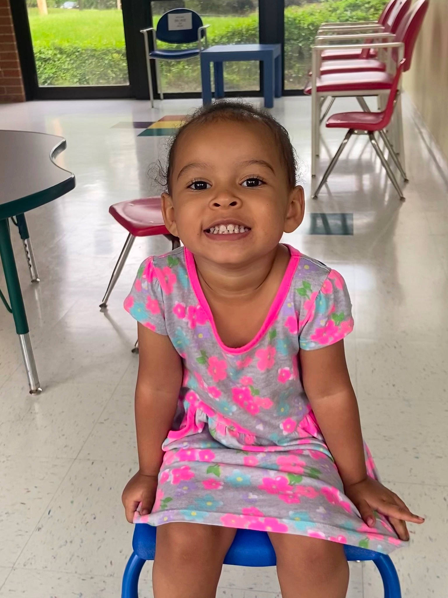 Milani is registered to the contest to win money with this photo: baby_toddler_clothing, chair, cheek, child, flooring, fun, happy, joy, leisure, magenta, person, pink, sitting, skin, sleeve, smile, snapshot, t_shirt, toddler, vacation