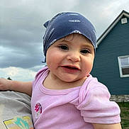 Ceylin is registered to the contest to win money with this photo: baby, child, bandana, pink_shirt, smile, drool, outdoor, house, blue_sky, cloudy, person, portrait, cute, holding, grass, headwear, face, cheerful, casual_clothing, daylight