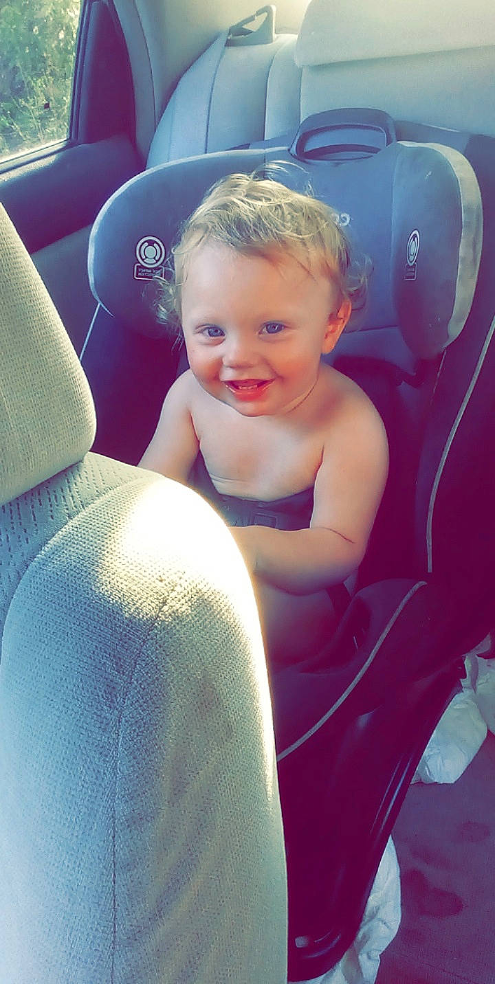 Carson is registered to the contest to win money with this photo: auto_part, automotive_design, automotive_exterior, car_seat, car_seat_cover, comfort, electric_blue, face, happy, head, head_restraint, joy, leg, light, motor_vehicle, person, sitting, smile, thigh, toddler