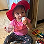 toddler, child, hat, pink_shirt, grey_pants, sitting, floor, toy, xylophone, toy_car, cheerful, smiling, indoors, playtime, plastic_container, shoes, red_hat, happy, cute, object_in_hand