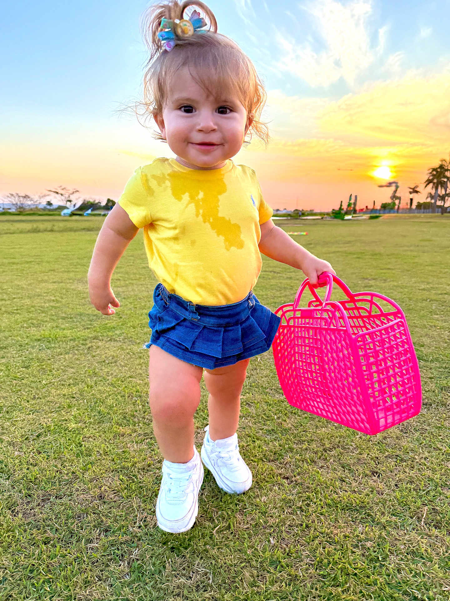 Aspen joined the competition — help win amazing prizes! toddler, child, yellow_shirt, blue_skirt, white_sneakers, pink_basket, grass, sunset, outdoor, happy, smiling, person, field, hair_bow, play, nature, sun, sky, casual_clothing, daylight