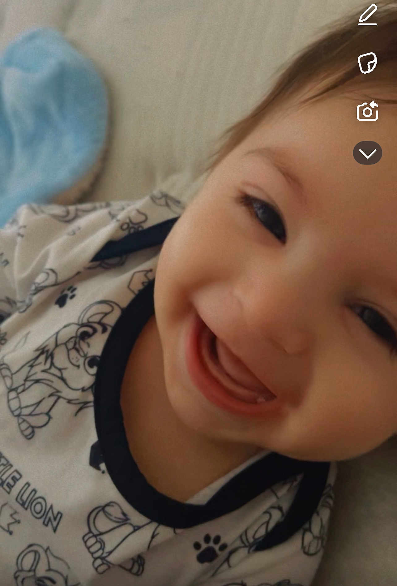 Ghaith is registered to the contest to win money with this photo: baby, infant, smile, close_up, face, teeth, onesie, patterned_clothing, paw_print, bed, pillow, blanket, happy, cute, portrait, indoor, lying_down, expression, soft_lighting, candid