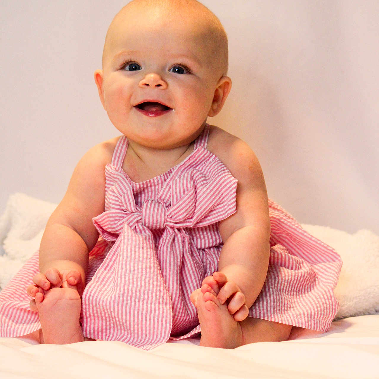 Ripley joined the competition — help win amazing prizes! baby, barefoot, bow, child, chubby_cheeks, cute, eyes, face, feet, hands, happy, indoor, infant, pink_dress, portrait, sitting, skin, smile, soft_toys, white_background