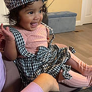 Maddison joined the competition — help win amazing prizes! toddler, child, happy, laughing, indoor, couch, beret, houndstooth, dress, pink_clothing, sitting, person, face, smiling, home, furniture, floor, television, arm, support