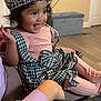 toddler, child, happy, laughing, indoor, couch, beret, houndstooth, dress, pink_clothing, sitting, person, face, smiling, home, furniture, floor, television, arm, support