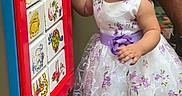 Ciara is registered to the contest to win money with this photo: toddler, child, girl, dress, purple_bow, playground, play_panel, carpet, curious, indoor, person, footwear, sock, shorts, adult, pattern, floral, colorful, toy, exploring
