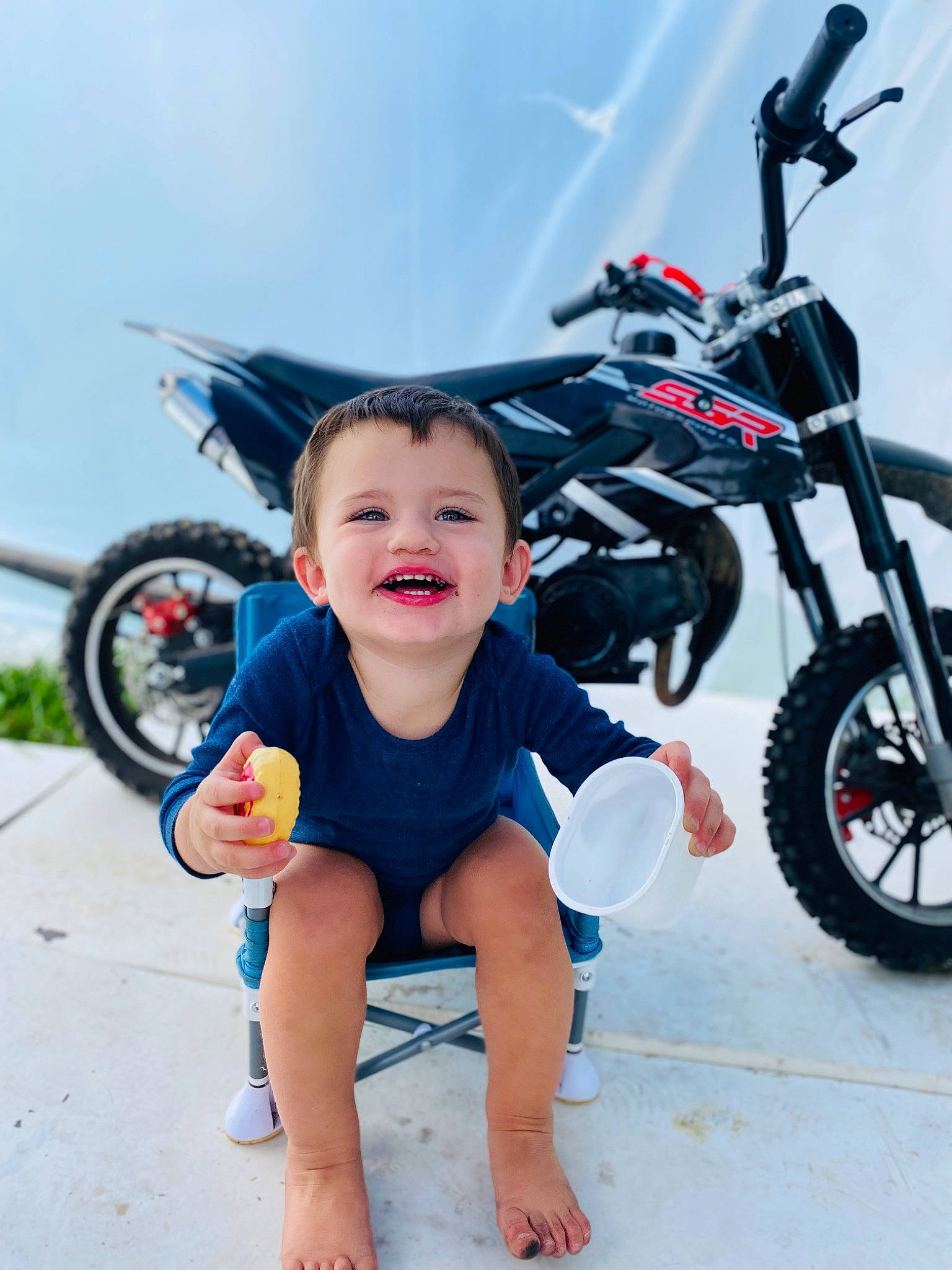 Bennett is registered to the contest to win money with this photo: auto_part, automotive_design, automotive_lighting, automotive_tire, automotive_wheel_system, baby_toddler_clothing, fender, happy, joy, leg, motor_vehicle, motorcycle, person, recreation, rim, smile, spoke, tire, toddler, travel
