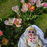 Odie joined the competition — help win amazing prizes! baby, tulips, grass, sunglasses, headband, blanket, smile, outdoor, flower_bed, yellow_clothing, spring, nature, happy, child, greenery, sunlight, cute, infant, playful, colorful