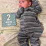 baby, infant, newborn, clothing, onesie, nike, striped, blanket, floral, milestone_card, text, lying_down, cute, small, person, footed_pajamas, sleepwear, indoors, portrait, child