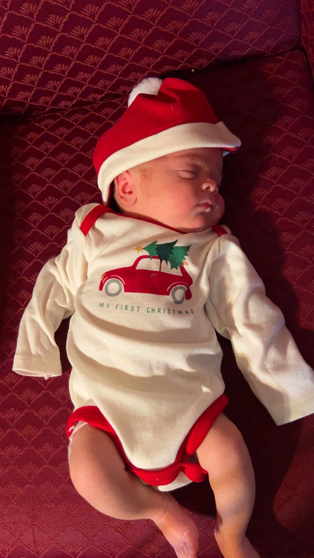 Enzo is registered to the contest to win money with this photo: baby, sleeping, infant, christmas, holiday, santa_hat, onesie, red, white, cute, peaceful, child, festive, cozy, maroon, fabric, clothing, portrait, lying_down, indoors