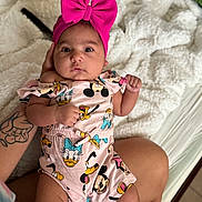 Arielle is registered to the contest to win money with this photo: baby, infant, pink_bow, headband, disney_characters, mickey_mouse, donald_duck, pluto, clothing, cute, person, portrait, hand, tattoo, blanket, bed, legs, skin, indoors, comfort
