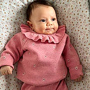 Elya a rejoint le concours — aidez-le/la à gagner de superbes lots ! baby, infant, pink_clothing, knitwear, blanket, patterned_blanket, heart_pattern, cute, portrait, child, soft_lighting, indoor, closeup, smiling, lying_down, cozy, warm_colors, small_hands, curly_hair, cute_outfit