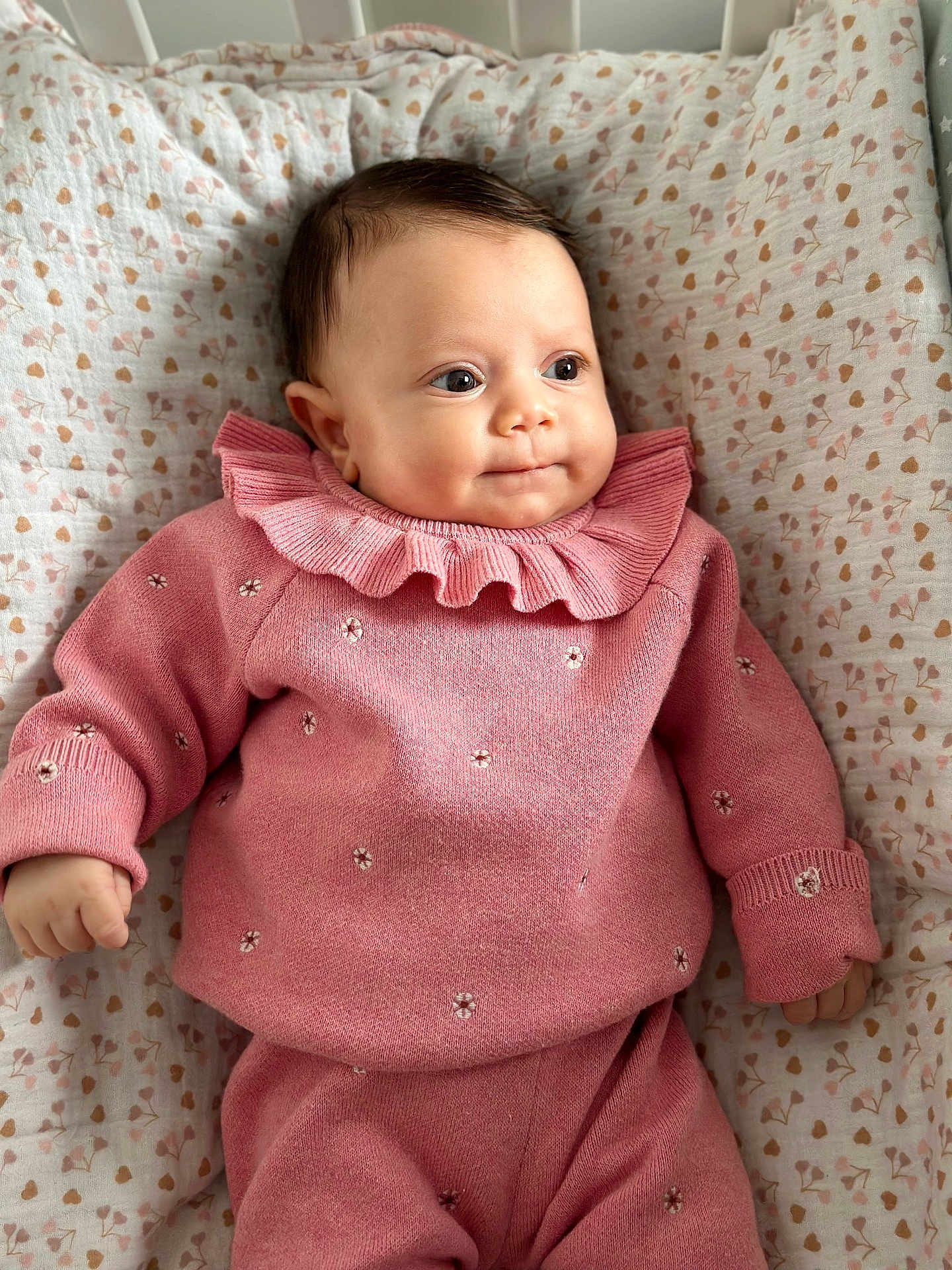 Elya a rejoint le concours — aidez-le/la à gagner de superbes lots ! baby, infant, pink_clothing, knitwear, blanket, patterned_blanket, heart_pattern, cute, portrait, child, soft_lighting, indoor, closeup, smiling, lying_down, cozy, warm_colors, small_hands, curly_hair, cute_outfit