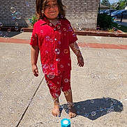 Gabriel is registered to the contest to win money with this photo: child, barefoot, red_clothing, soap_bubbles, bubble_machine, outdoor, sunny, sidewalk, concrete, brick_wall, shadow, happy, playful, summer, casual, person, shorts, smile, daytime, nature