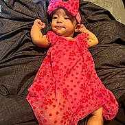 Leilani is registered to the contest to win money with this photo: baby, infant, child, pink_dress, headband, bow, red_hearts, blanket, lying_down, fabric, cute, indoors, portrait, young_child, resting, skin, hands, legs, person, comfortable