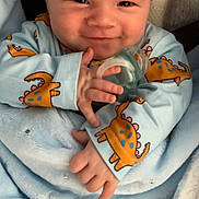 Jake joined the competition — help win amazing prizes! baby, babywear, blanket, child, clothing, cozy, cute, dinosaur_print, face, hand, happy, indoors, infant, pacifier, person, portrait, sitting, smile, soft, young