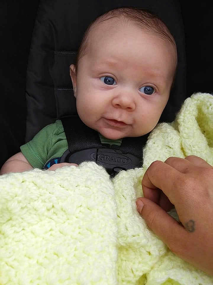Tucker is registered to the contest to win money with this photo: arm, baby, beauty, blanket, cheek, child, eye, face, green, hand, head, nose, outerwear, person, product, skin, smile, textile, toddler, wool