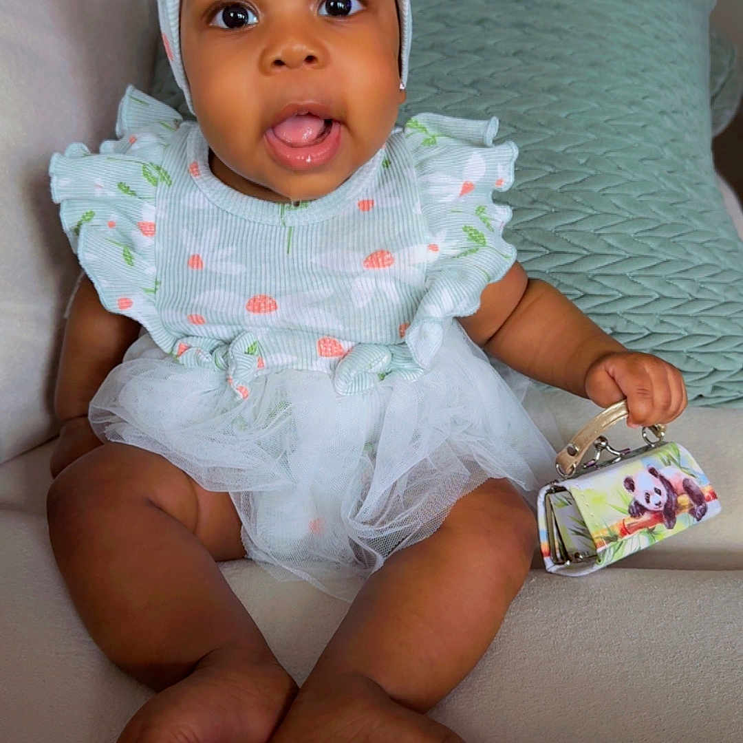 Leilany joined the competition — help win amazing prizes! baby, child, infant, headband, bow, dress, tutu, purse, panda_print, couch, cushion, indoor, smiling, happy, cute, person, sitting, soft_furniture, cozy, portrait