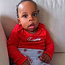 baby, casual, child, clothing, comfortable, couch, curious, cute, expression, floral_pants, furniture, indoor, infant, person, portrait, red_shirt, relaxed, sitting, wide_eyes, young_child