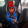 Thomas is registered to the contest to win money with this photo: child, car_seat, car_interior, spiderman_jacket, glasses, red_box, orange_glasses, seatbelt, window, road, trees, car, child_in_car, blue_jacket, casual_clothing, sitting, vehicle, daytime, funny, kid