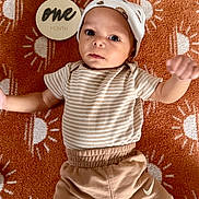 Benjamin is registered to the contest to win money with this photo: baby, infant, one_month, blanket, orange, sun_pattern, striped_shirt, hat, pants, socks, face, eyes, person, child, laying_down, indoors, cute, cozy, newborn, portrait