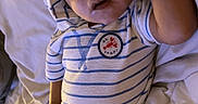 Benjamin joined the competition — help win amazing prizes! baby, infant, striped_onesie, hood, bed, white_sheets, looking_up, hand_on_head, curious, cute, child, young, portrait, indoors, person, sleepwear, relaxed, small, adorable, toddler