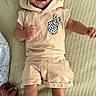 baby, child, smiling, beige_outfit, peace_sign, checkered_pattern, lying_down, happy, infant, hand, tattoo, white_socks, textured_surface, cute, portrait, young_child, person, indoor, apparel, closeup