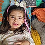 child, girl, smile, hair_bow, pink_hair_extensions, food, pillow, blanket, clothing, sitting, indoors, happy, cute, tutu_skirt, long_hair, face, hand, cozy, colorful, portrait