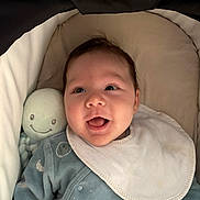 Jonah Mercier a rejoint le concours — aidez-le/la à gagner de superbes lots ! baby, infant, newborn, smiling, bib, onesie, plush_toy, octopus_toy, bassinet, stroller_linings, blanket, cozy, portrait, face, cheeks, eyes, mouth, happy, lying_down, clothing