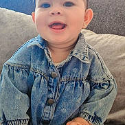 Mira a rejoint le concours — aidez-le/la à gagner de superbes lots ! baby, child, denim_jacket, headband, smiling, happy, indoor, couch, pillows, cute, portrait, sitting, clothing, face, hand, earrings, long_sleeves, patterned_tights, cozy, infant