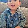 baby, child, denim_jacket, headband, smiling, happy, indoor, couch, pillows, cute, portrait, sitting, clothing, face, hand, earrings, long_sleeves, patterned_tights, cozy, infant