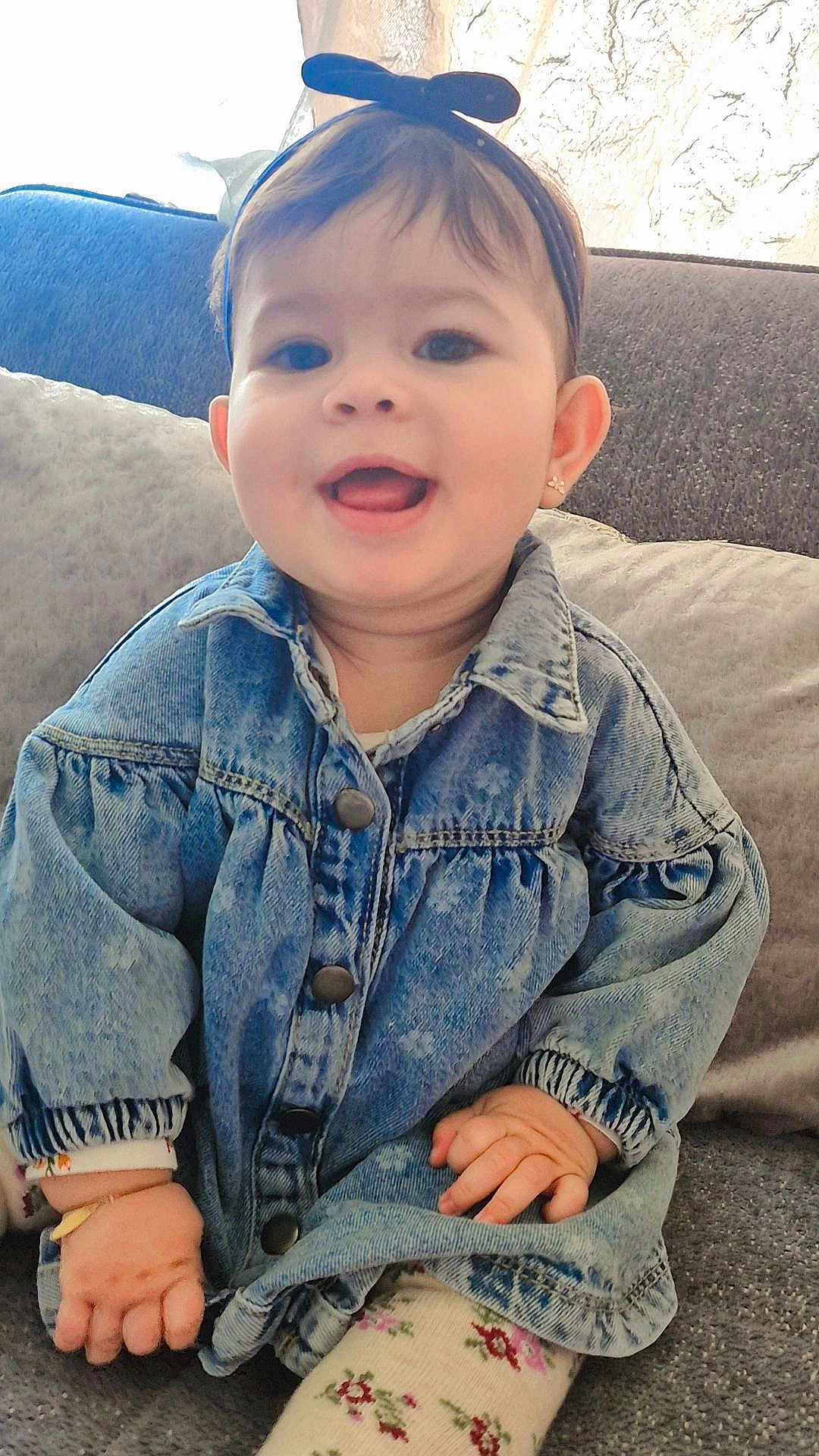Mira a rejoint le concours — aidez-le/la à gagner de superbes lots ! baby, child, denim_jacket, headband, smiling, happy, indoor, couch, pillows, cute, portrait, sitting, clothing, face, hand, earrings, long_sleeves, patterned_tights, cozy, infant