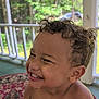 Zehri joined the competition — help win amazing prizes! toddler, child, smiling, curly_hair, laughing, bare_chest, porch, rug, patterned_rug, outdoor, daylight, greenery, railing, happy, cute, skin, person, face, young_child, natural_light