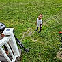 child, smiling, grass, outdoor, lawn, scooter, helmet, stairs, adult, person, white_tshirt, boots, greenery, daylight, happy, play, nature, recreation, garden, curly_hair