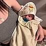 baby, towel, hood, pacifier, person, adult, arm, clothing, necklace, heart, winnie_the_pooh, indoor, holding, skin, gray_tank_top, blanket, comfort, cute, child, calm