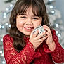child, girl, smiling, red_dress, lace, long_hair, christmas_tree, ornament, disco_ball, holiday, celebration, festive, happy, portrait, indoors, decoration, seasonal, cute, young, joyful