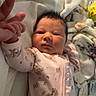 Alannah is registered to the contest to win money with this photo: baby, infant, pink_onesie, cartoon_print, blanket, hand_holding, adult_hand, bed, cozy, newborn, cute, sleepwear, face, skin, person, lying_down, fingers, soft, indoor, comfort