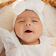 Léna participe au concours pour gagner de l'argent avec cette photo : baby, infant, white_clothing, headband, bow, close_up, smiling, happy, soft_light, portrait, cute, child, newborn, skin, face, expression, fabric, texture, warm, cozy