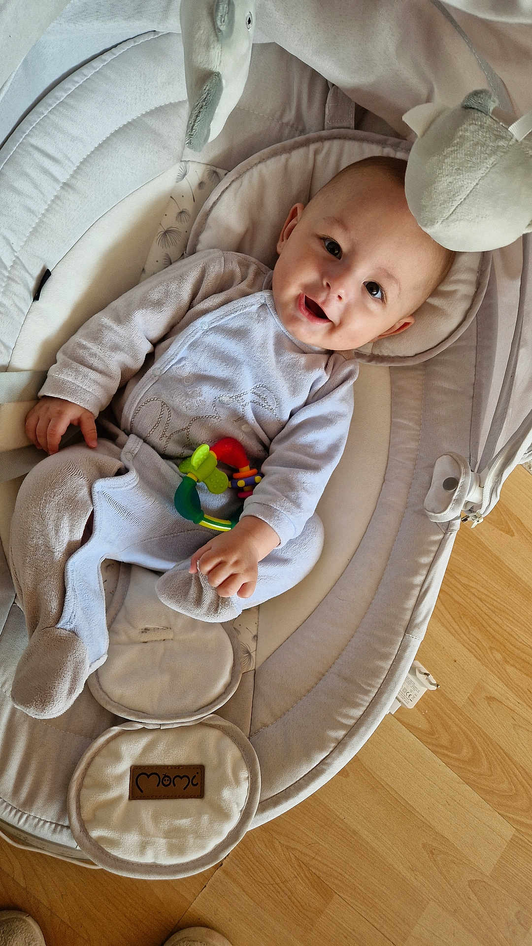 Adam participe au concours pour gagner de l'argent avec cette photo : baby, infant, pajamas, toy, baby_rocker, smiling, face, cushion, floor, wooden_floor, hand, footwear, head, person, indoor, comfort, child, play, clothing, happy