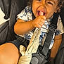 baby, black_harness, candid, child, closeup, cloth_toy, curly_hair, cute, grip, happy, indoors, palm_tree, pattern, playful, seat, shirt, shorts, smiling, stroller, toddler