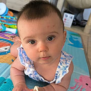 Ella participe au concours pour gagner de l'argent avec cette photo : baby, child, closeup, clothing, colorful, curious, expression, eyes, face, floor, hand, indoor, infant, pattern, person, play_mat, skin, sleeveless, toy, young