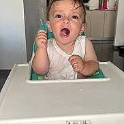 Ishay a rejoint le concours — aidez-le/la à gagner de superbes lots ! baby, cabinet, child, excited, expression, feeding, floor, furniture, high_chair, home, indoor, kitchen, messy, mouth_open, person, refrigerator, seat, toddler, wet_hair, white_shirt